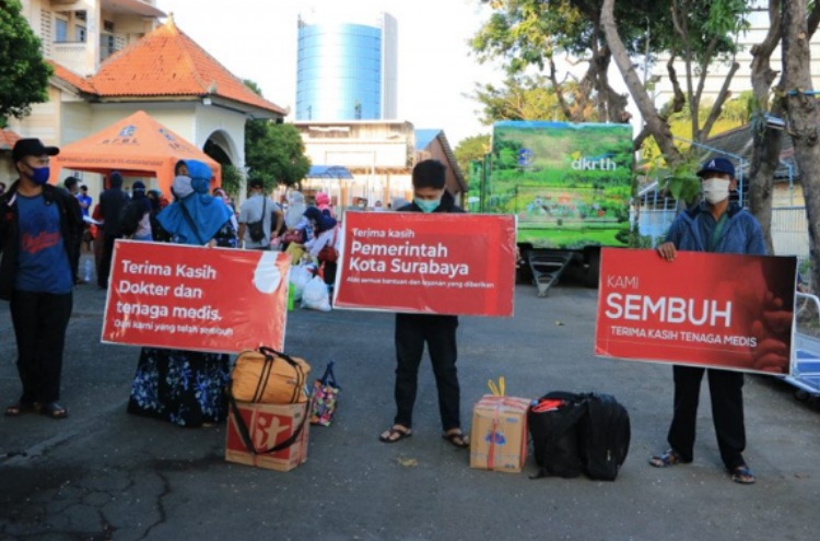 Sejumlah warga yang dinyatakan sembuh dari Covid-19 membawa spanduk bertuliskan ucapan terima kasih kepada tenaga medis di Surabaya. SP/MI