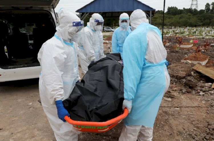 Pekerja pemakaman yang mengenakan pakaian pelindung membawa tubuh korban penyakit virus corona (Covid-19) di sebuah pemakaman di Shah Alam. SP/ Reuters