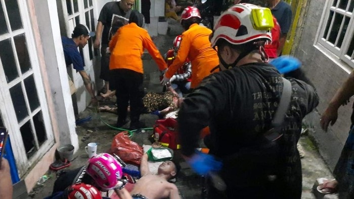 Petugas BPBD sedang mengevakuasi korban kebakaran, yakni pelaku tak lain suami dan istri dan dua anaknya dari rumahnya di daerah Jalan Dukuh Bulu, Lontar, Surabaya, Jumat (14/4/2023)