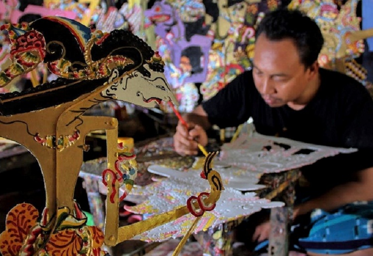 Hartono yang tengah mengerjakan pesanan kerajinan wayang kulit. SP/ MJK