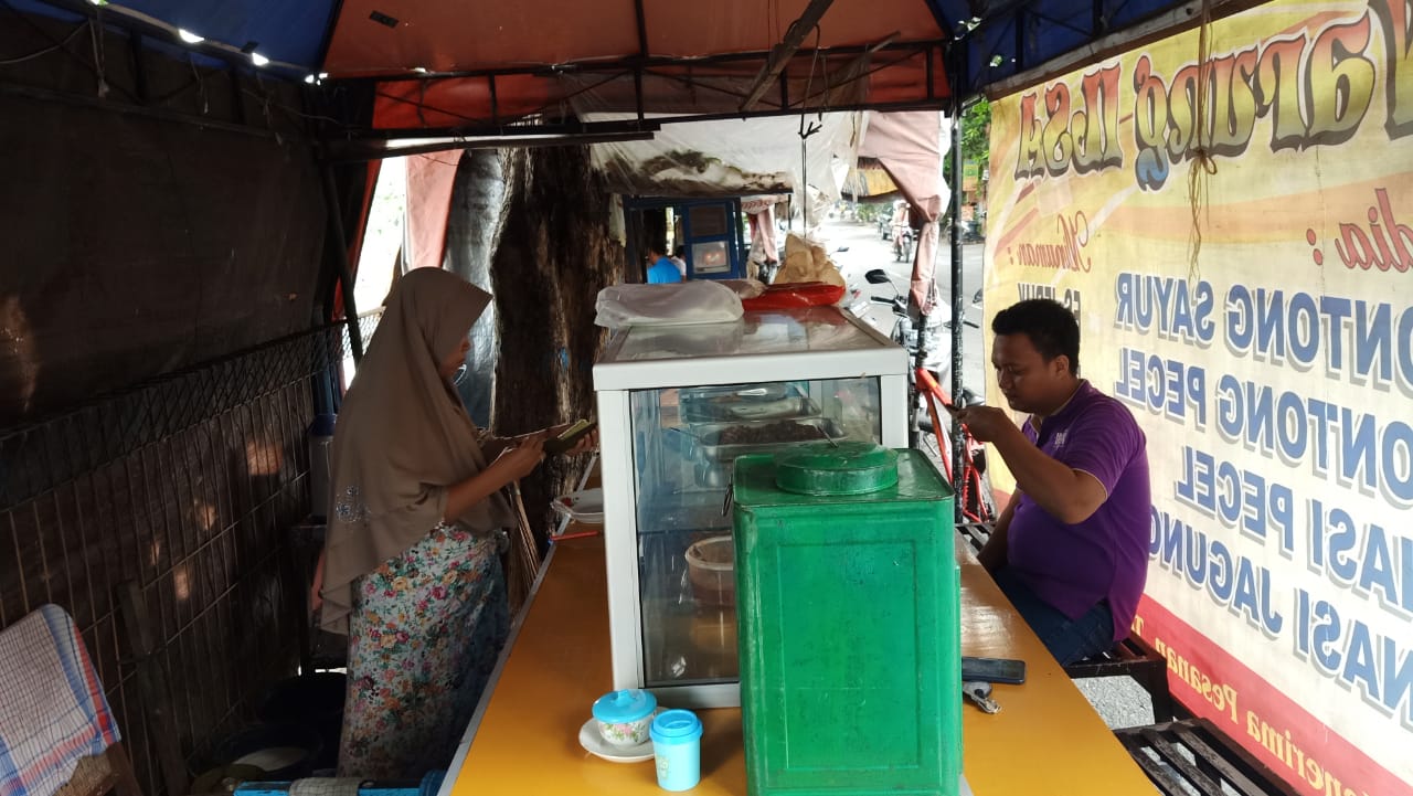 Caption: Erna penjual nasi jagung, pecel dan sayur lontong tengah melayani pembeli di lapak miliknya PKL Jalan Laras Liris. SP/MUHAJIRIN KASRUN