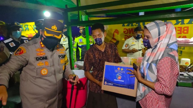 Kapolres Mojokerto saat memborong puluhan bungkus nasi dan mie Goreng pelanggar jama malam PPKM Skala 3 dan 4.  SP/Dwy AS