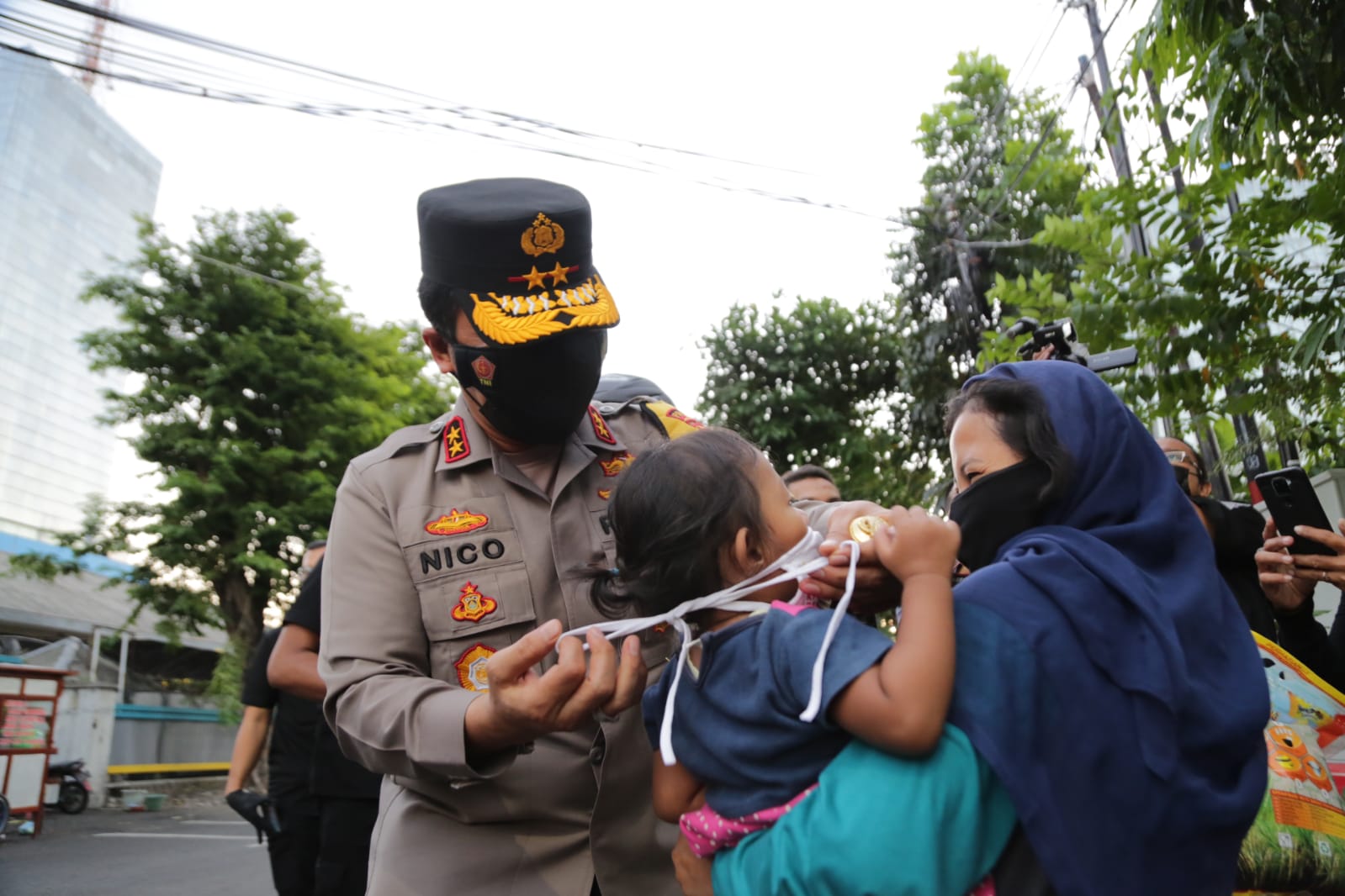 Kapolda Jatim Irjen Pol Nico Afinta memberikan masker kepada anak kecil yang digendong orangtuanya dan memberikan bantuan sembako, Sabtu (24/7/2021)