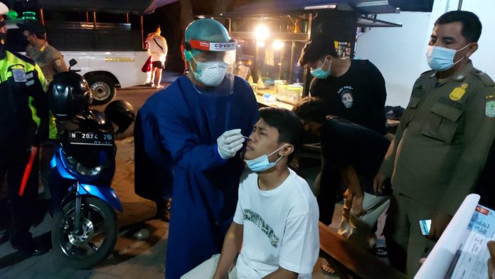 Petugas melakukan tes swab kepada para pengunjung warkop.