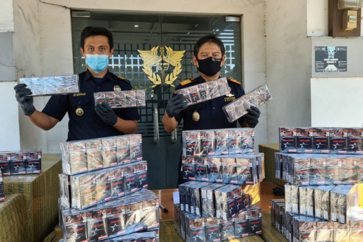 Petugas menunjukkan puluhan ribu rokok polos atau pita cukai yang berhasil diamankan. 