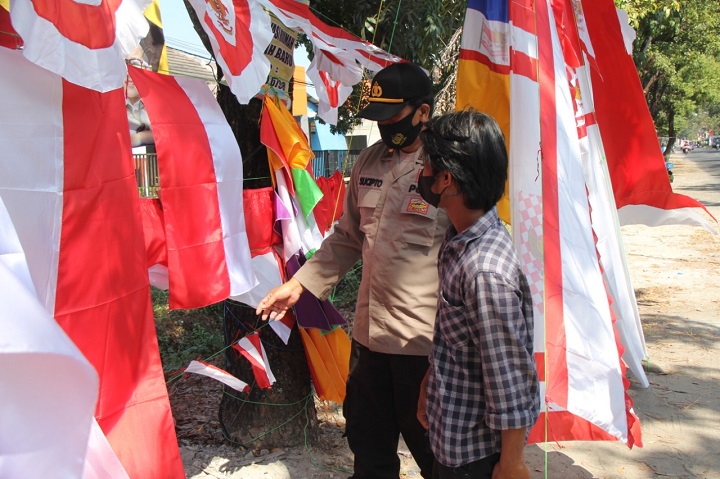 Personel Polres Lamongan saat membeli bendera merah putih ke pedagang. SP/MUHAJIRIN KASRUN