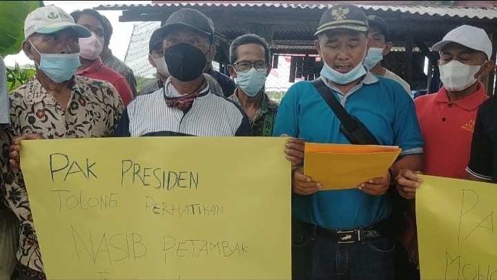 Perwakilan petani tambak di Lamongan membentangkan kertas karton bertuliskan tuntutan pemenuhan pupuk bersubsidi secara permanen/ foto: Muhajirin Kasrun