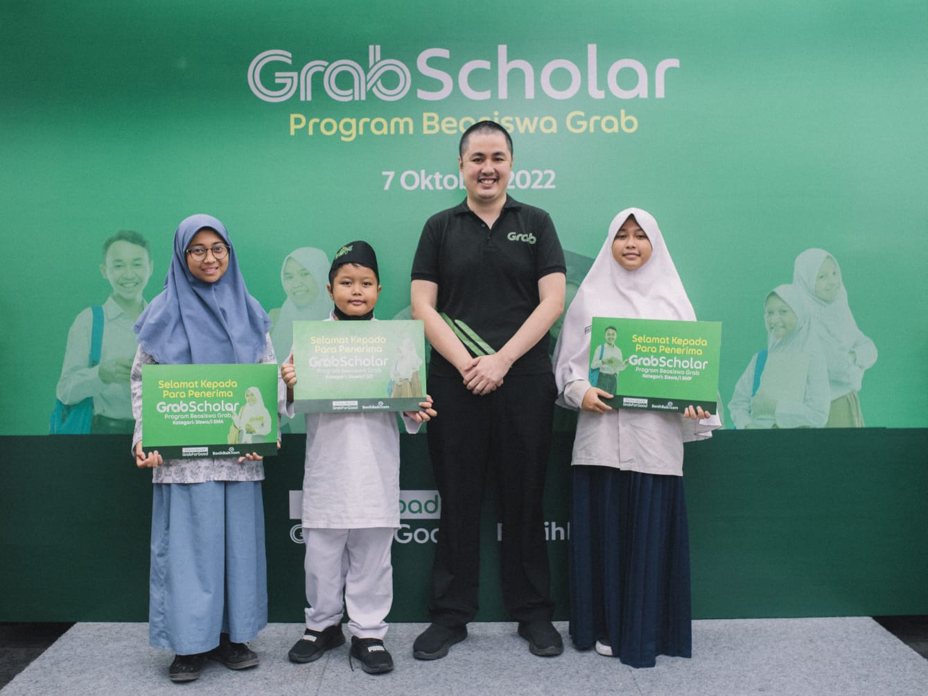 Para anak mitra berprestasi yang menerima program beasiswa GrabScholar: Program Beasiswa Grab 2022 di Surabaya berfoto bersama perwakilan Grab
