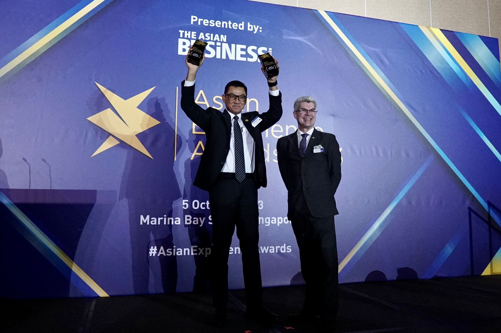 Simon Hyett (kanan) menyerahkan piala penghargaan Indonesia User Experience of the Year dan Indonesia Digital Experience of the Year kepada Direktur Utama PLN, Darmawan Prasodjo (kiri) saat Asian Experience Awards 2023 di Singapura, Kamis (5/10/2023). Fot