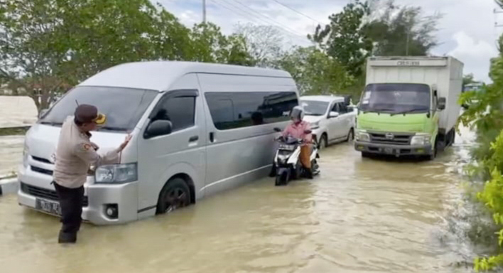Personel Polres Sumenep saat mengamankan arus lalu lintas di tengah kondisi banjir. SP/Ariandi.