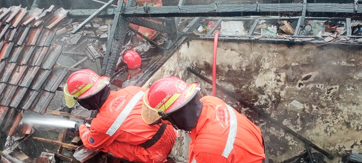 Petugas saat memadamkan api yang membakar bangunan. SP/Ariandi