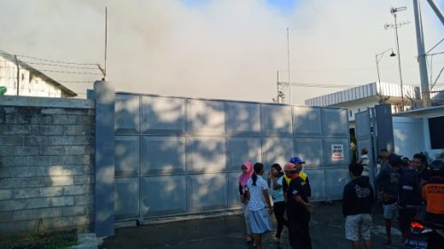 Asap tebal terbakarnya pabrik terlihat dari depan pintu masuk pabrik. 