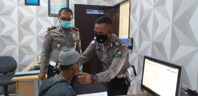 Peserta Ujian Teori saat diberi masker oleh Brigpol Masrukin di saksikan Kasat Lantas AKO.Tri Nuartiko.
