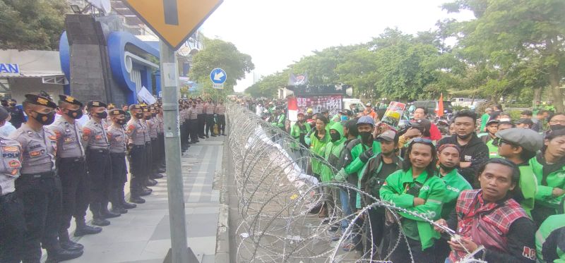 Aksi para driver online dijaga ketat polisi dan kawat berduri.