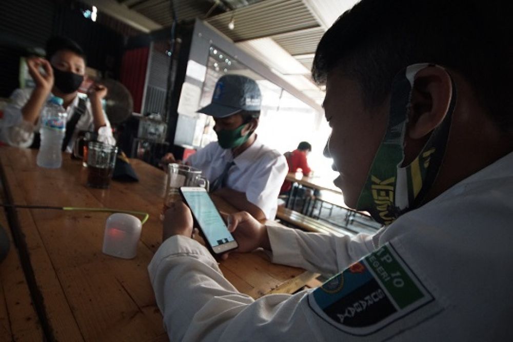Siswa melakukan sekolah virtual dengan memanfaatkan wifi di warkop Pitulikur kawasan jalan Bagong Tambangan Surabaya, Selasa (21/7/2020). Siswa memilih belajar di Warkop karena pelaksanaan belajar dari rumah membutuhkan jaringan internet.
Foto: SP/Julian