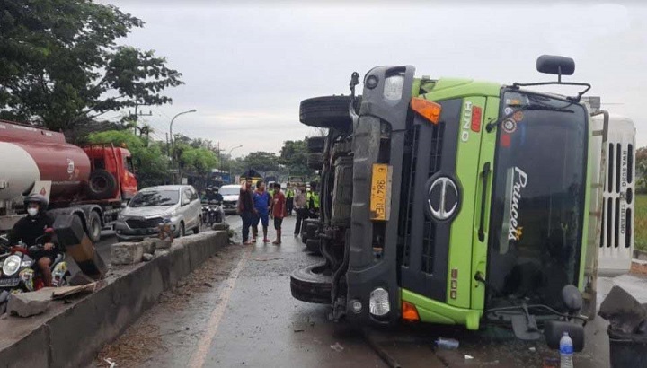 Kondisi truk boks terguling usai naik trotoar atau pembatas tengah jalan persimpangan.