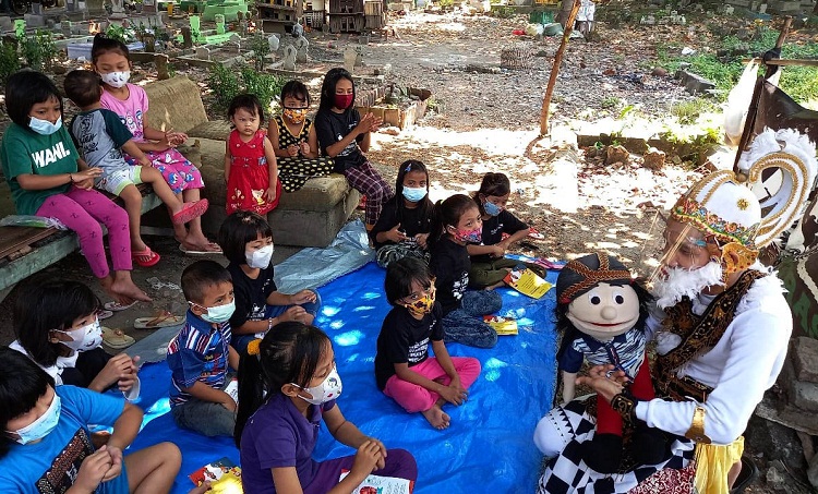 Pendongeng Harris Rizki Akhiruddin atau Kak Harris mengenakan kostum Kera Putih Hanoman bersama boneka Ayis menghibur anak-anak di komplek pemakaman Rangkah Kota Surabaya. SP/ Patrick Cahyo