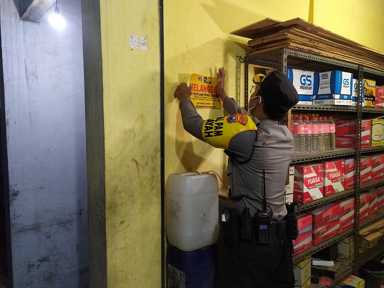 Kompol Bambang Prakoso menempel Stiker Pelanggaran terhadap pedagang yang melanggar aturan jam malam. SP/ Ang