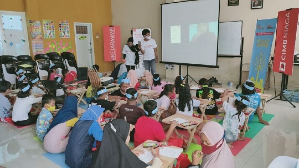 Bagus Pramudita Koordinator Volunteering Activity dari Kejar Mimpi (Kanan) menyerahkan cindera mata pada perwakilan  anak - anak di Yayasan Taman Baca Rumah Kita, Surabaya, Jawa Timur, Rabu (30/9). SP/Patrik Cahyo