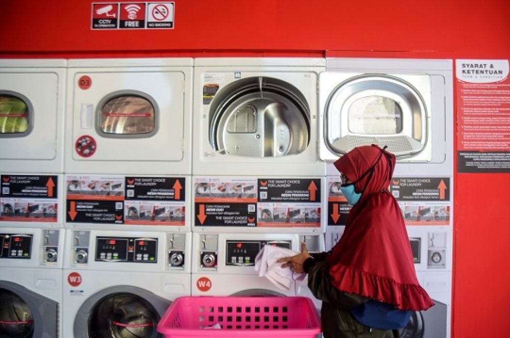Nina pelanggan laundry mengambil pakaian seragam sekolah yang selesai dikeringkan menggunakan mesin cuci IPSO di Jalan Aryo Bebangah, Wage, Sidoarjo, Jawa Timur, Selasa (28/7. SP/Patrik Cahyo 