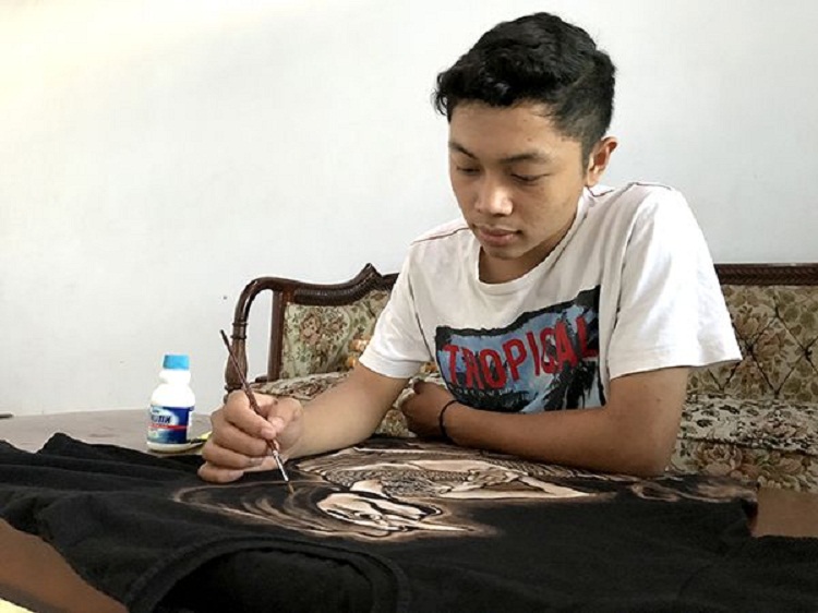 Muhamad Yuli Wibisono sedang melukis di kaos polos. SP/ TLG