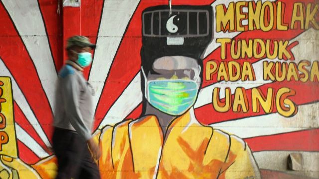 Pejalan kaki ditengah pandemi menggunakan masker di depan mural saat pemilihan kepala daerah serentak 2020 lalu. (Foto: SP/antara)