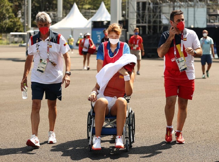 Paula Badosa, petenis asal Spanyol menggunakan kursi roda akibat terik panas dibantu oleh staf dan tim Olimpiade Tokyo 2020. SP/ Getty Image