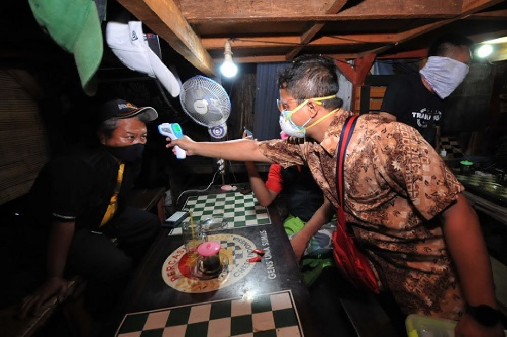 Salah satu petugas sedang mengecek suhu tubuh menggunakan thermo gun, saat melakukan penyegelan dan penertiban di sejumlah warung kopi di daerah Sawahan Surabaya, Sabtu (10/5/2020) malam.
Foto: SP/Julian
