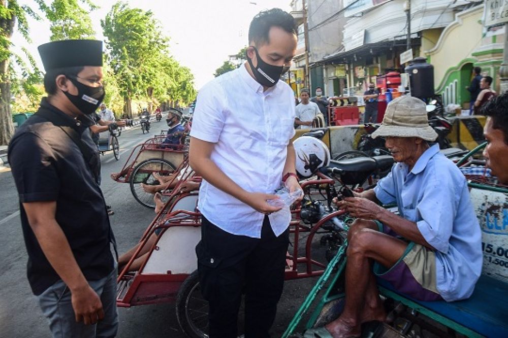 Firosya Shalati Wakil ketua Bala Bhineka membagikan masker pada tukang becak di Kawasan Wisata Religi Sunan Ampel. Surabaya, Jawa Timur, Jumat (18/9).SP/Patrik Cahyo
