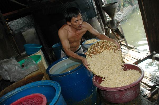 Salah seorang pengrajin tempe tengah memproduksi tempe.