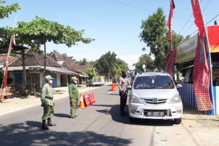 Petugas memeriksa kendaraan yang masuk ke kota Madiun. 