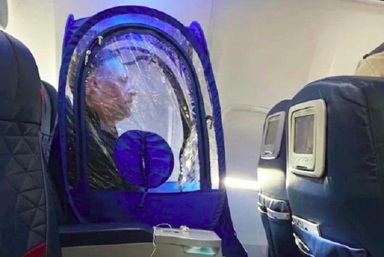 Rick duduk di bangku pesawat sambil mengenakan tenda mini buatannya. SP/ SBY