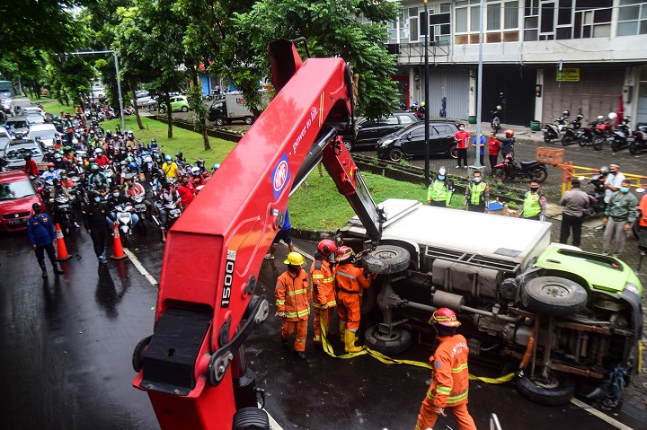 Petugas gabungan yang terdiri Linmas, Satpol PP, Kepolisian serta damkar mengevakuasi truk muatan buah yang terguling di Jalan Ir. Soekarno Merr, Kota Surabaya, Jawa Timur, Kamis (25/2). SP/Patrik Cahyo