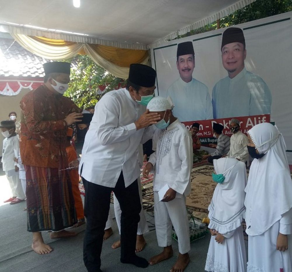 Qosim didampingi Alif mencium kening seorang anak yatim usai diberi santunan.SP/M AIDID