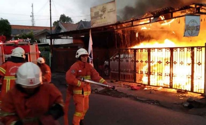 Petugas berjibaku memadamkan api yang membakar bangunan.