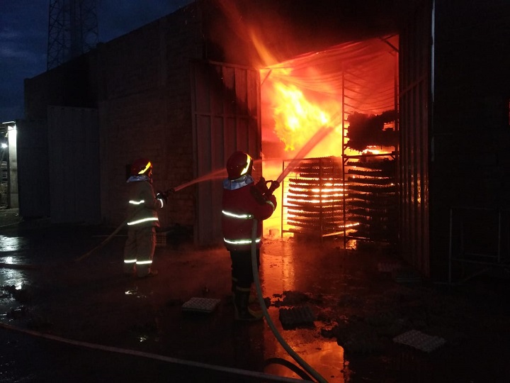 Petugas saat memadamkan api yang membakar pabrik. SP/Hadi Lestariono