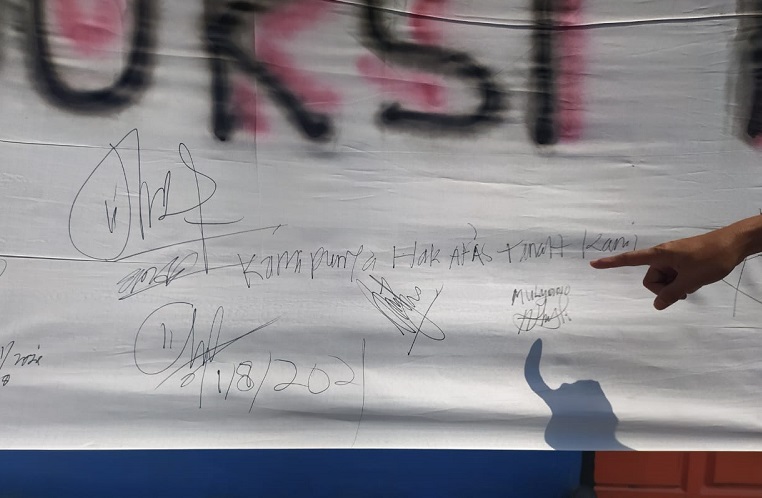 Warga menorehkan tanda tangan di spanduk penolakan gudang peti jenazah di Dusun Bolowono.