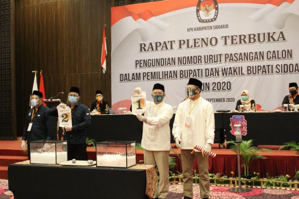 Cabup BHS dan cawabup Taufiqulbar  menunjukkan nomor undian 1 dan Muhdlor- Subandi nomor 2
