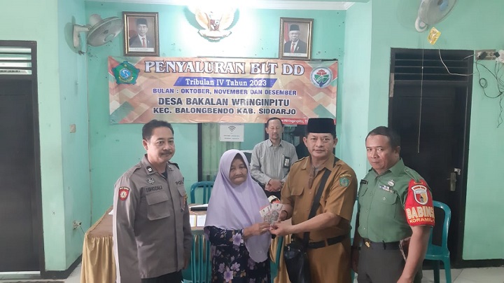 Kades Bakalan Wringinpitu, Nanang Heksa,  didampingi bhabinkamtibmas dan babinsa, saat  menyerahkan bansos BLT-DD tahun 2023 secara simbolis.