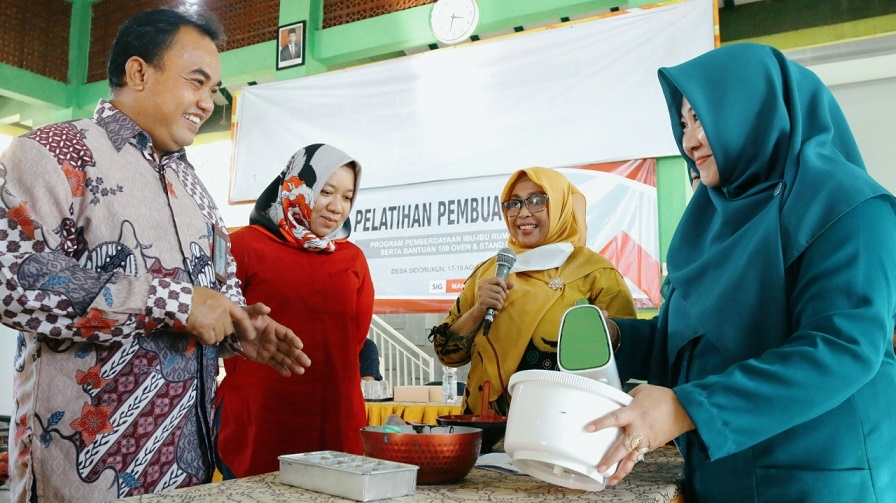 General Manager of CSR SIG Edy Saraya (kiri) didampingi Kabid Koperasi dan Usaha Mikro Dinas Koperasi, Usaha Mikro dan Perindag Kabupaten Gresik, Fransiska Dyah Ayu (dua dari kiri) melihat praktik pelatihan pembuatan kue di Desa Sidorukun,  Jumat (19/08).