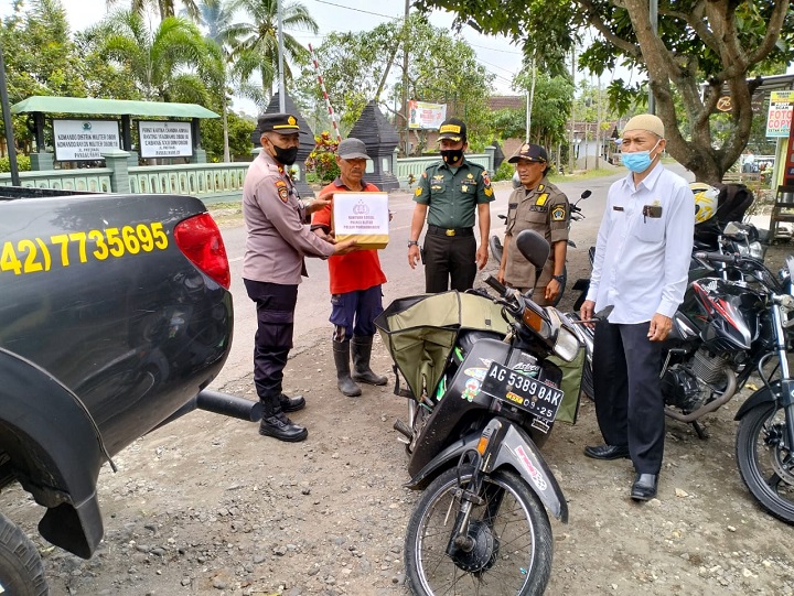 Kapolsek Panggungrejo Iptu Agus Purnomo, dan Kasi Sosial dan Staf Trantib Kec.Panggungrejo saat membagikan bansos kepada warga. SP/Hadi Lestariono