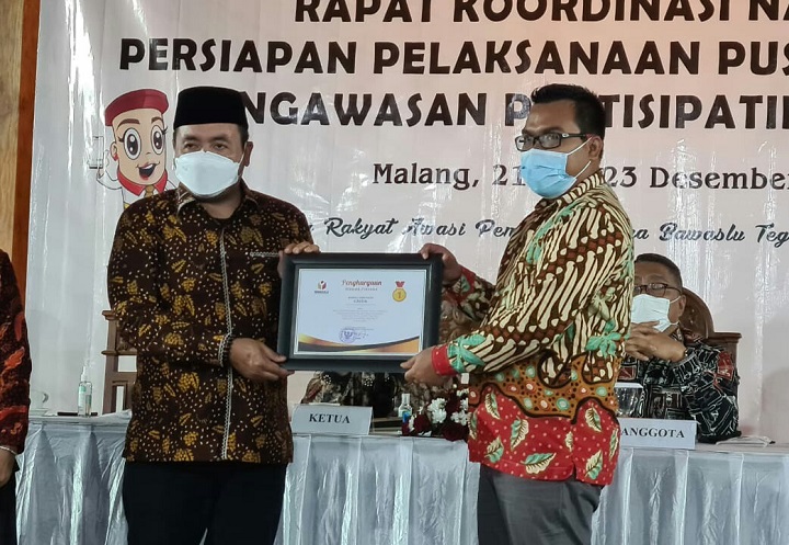 Komisioner Bawaslu Gresik M Syafi' Jamhari (kanan) saat menerima penghargaan dari komisioner Bawaslu RI M Afifuddin. SP/M.AIDID