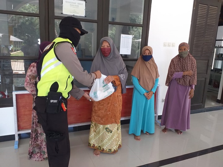 Anggota Polsek Tambak membagikan paket sembako kepada warga kurang mampu. SP/Grs