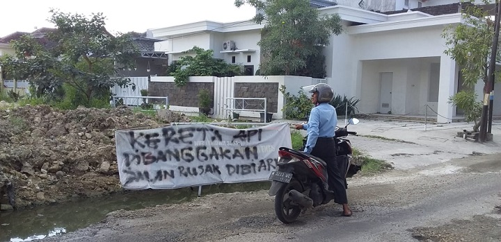 Areal jalan rusak dan banner bertuliskan "Kereta dibanggakan, jalan dibiarkan" di sepanjang jalan Adhirasa kota Sumenep. SP/Ainur Rahman