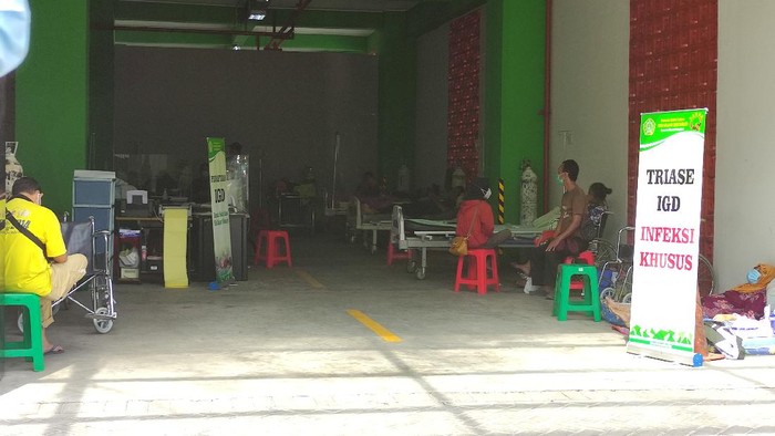 Beberapa pasien nampak dirawat di hall parkir yang diubah menjadi tempat perawaran karena kapasitas overload.