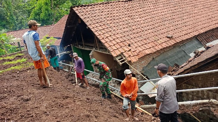 Petugas membersihkan material longsor yang merusak sejumlah rumah di Probolinggo