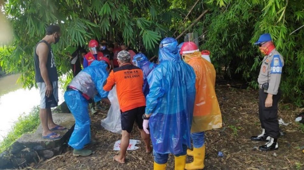 Petugas mengevakuasi jenazah yang ditemukan mengapung di sungai Joko Doyah dengan menggunakan APD sesuai protokol Kesehatan. 