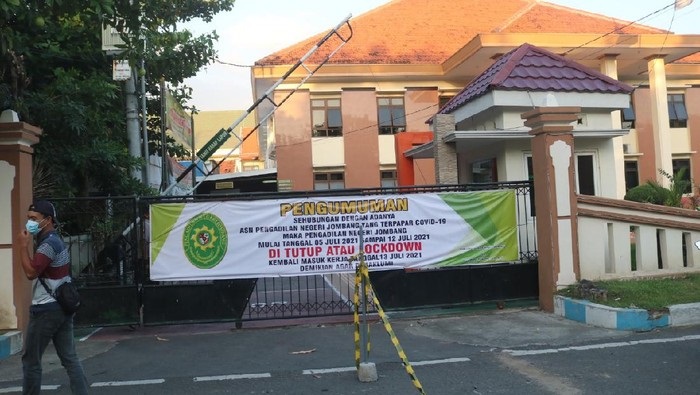 Pintu gerbang PN Jombang terpasang pengumuman PN dilockdown selama sepekan.