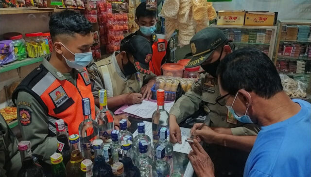 Petugas Satpol PP Kabupaten Kediri saat menyita puluhan botol miras dari warung di Wonorejo, Kecamatan Wates, Sabtu (23/10/2021) malam.