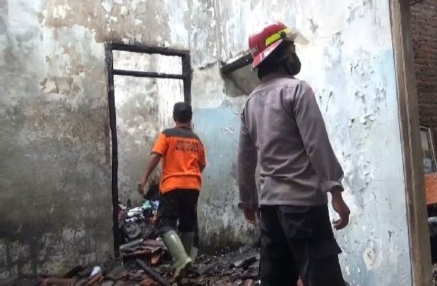 Petugas melakukan pembasahan di rumah Agus Warianto yang dibakar sang anak.